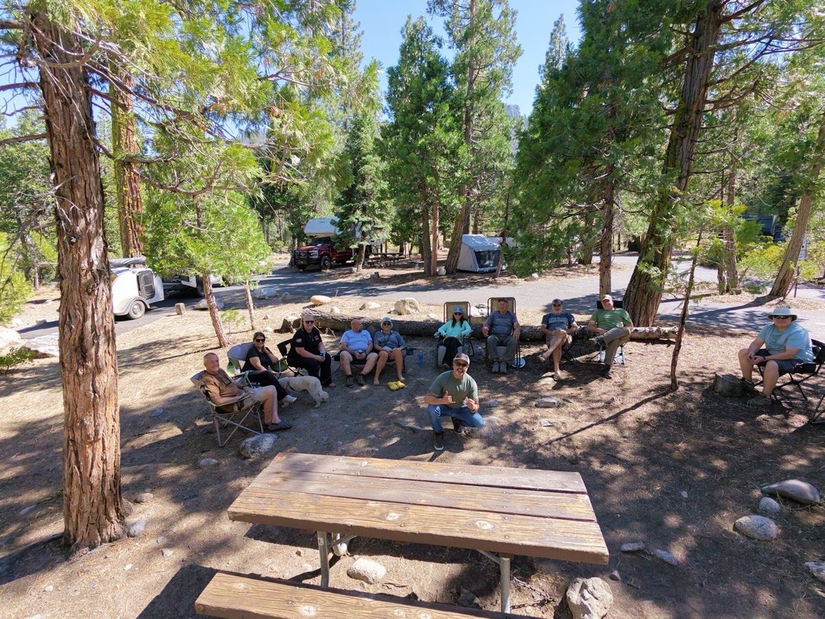 The group gathered in a circle at camp under the pines