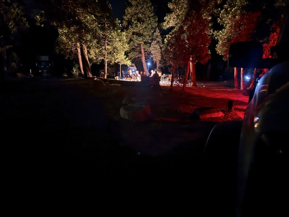 Campfire glow with red truck light at the campsite, night