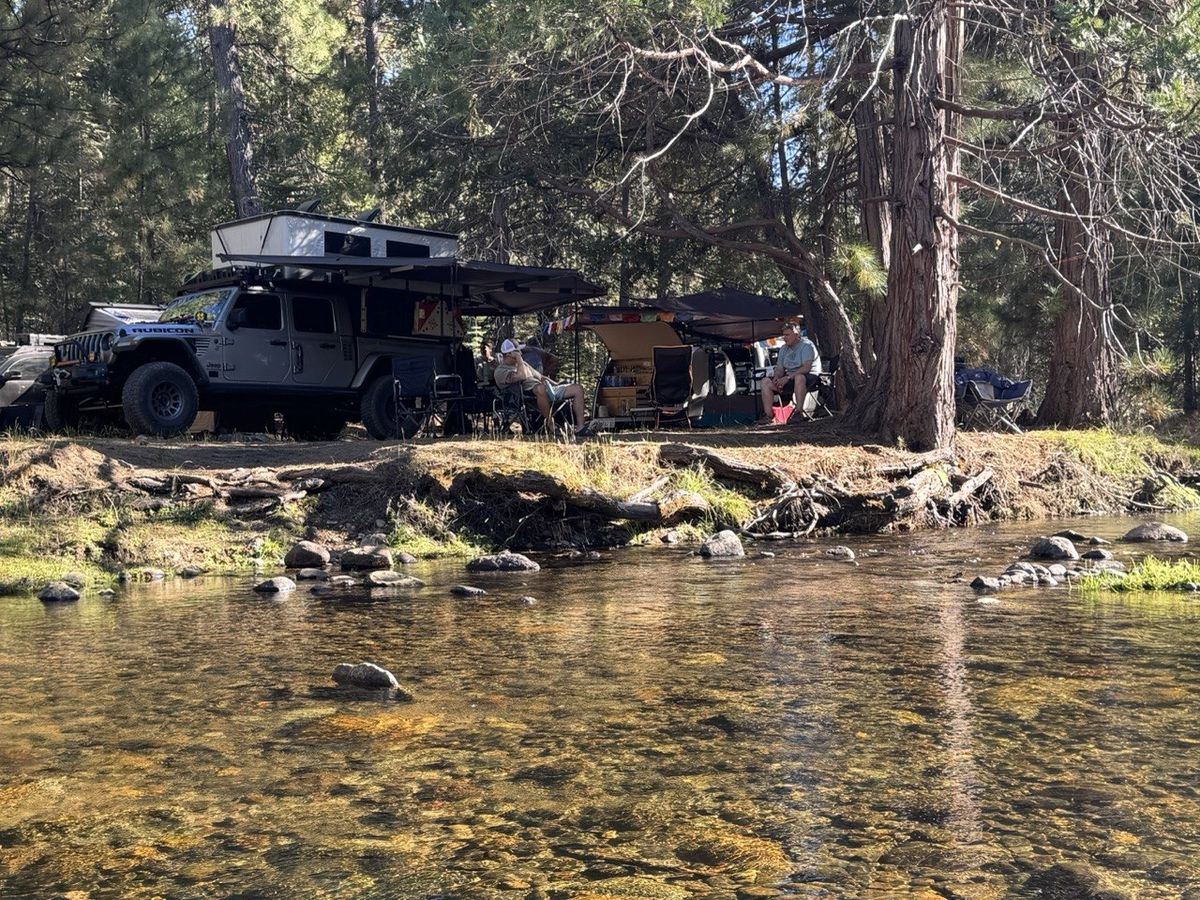 Gray Jeep Wrangler Rubicon with rooftop tent camped on the stream bank
