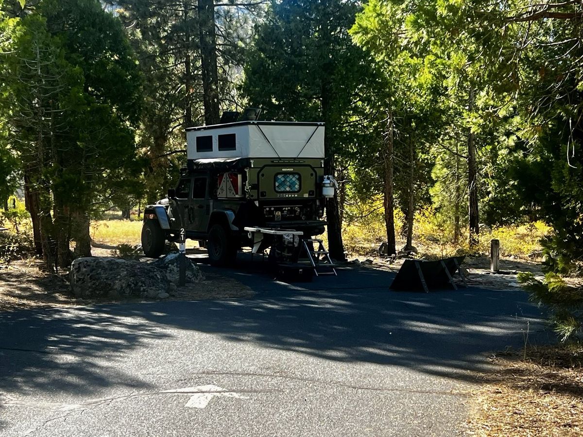 Dark Jeep with olive-green and white truck camper at site 211
