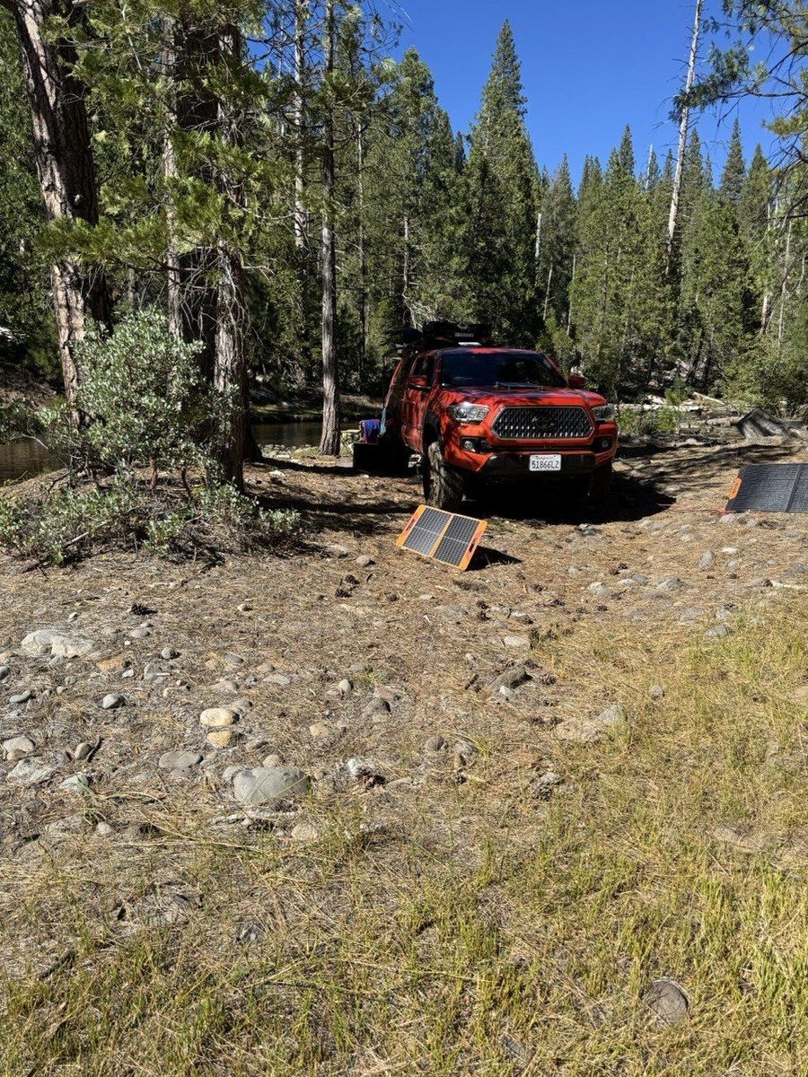 Red Tacoma with solar panels, off-grid riverside camp