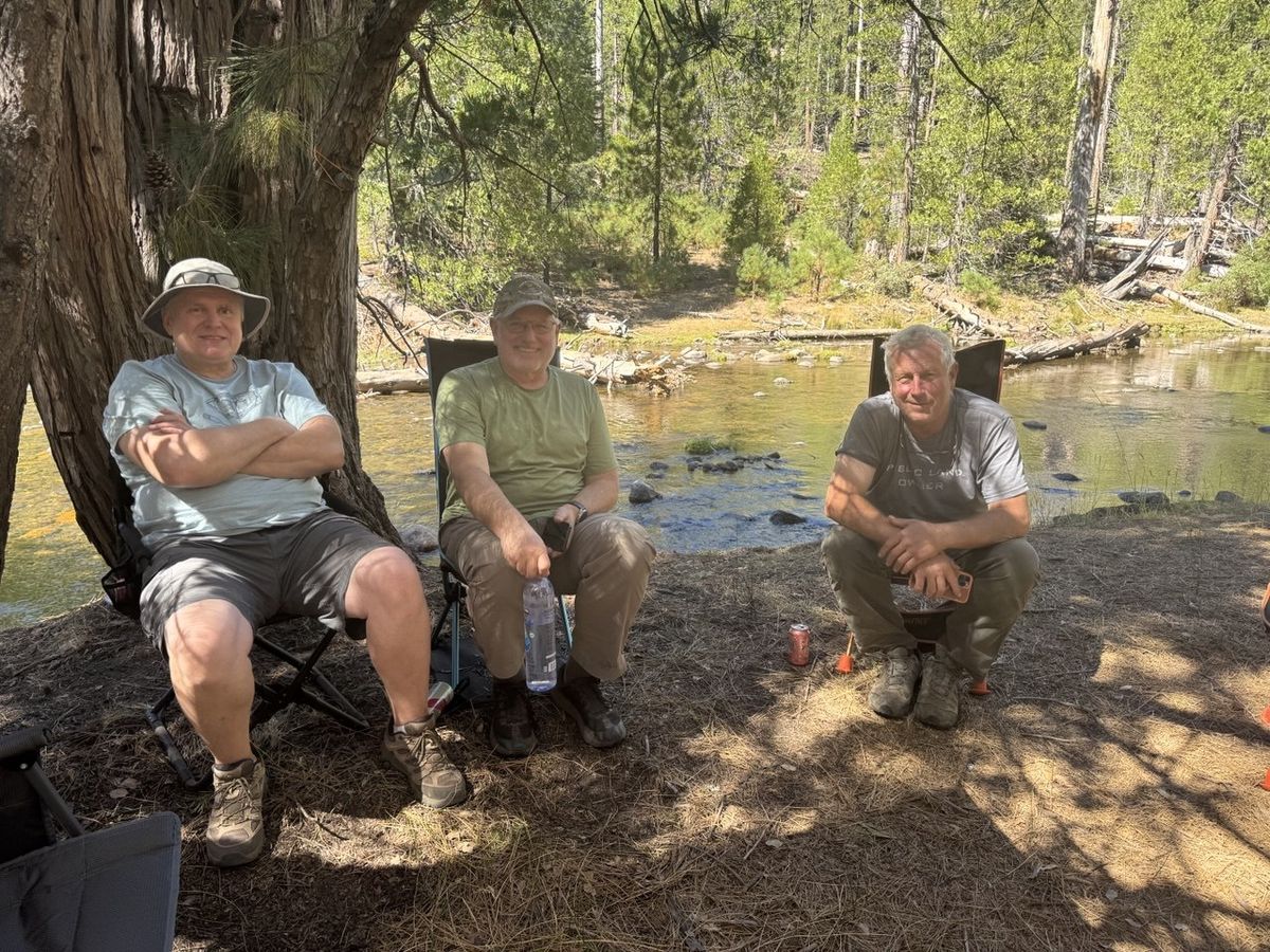 The guys relaxing on the riverbank under the pines