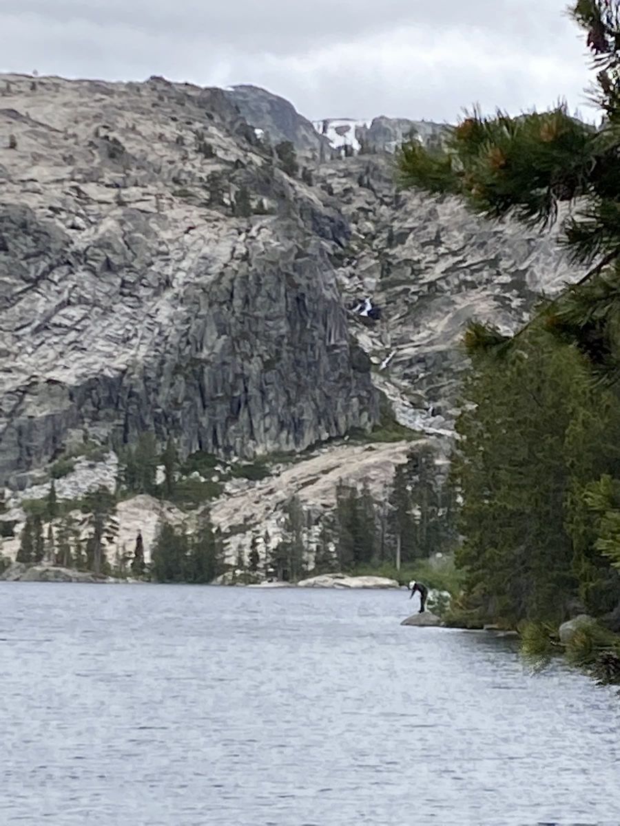 Alpine lake vista near Faucherie Lake basin with dramatic granite talus slopes, cascades, and rocky shoreline